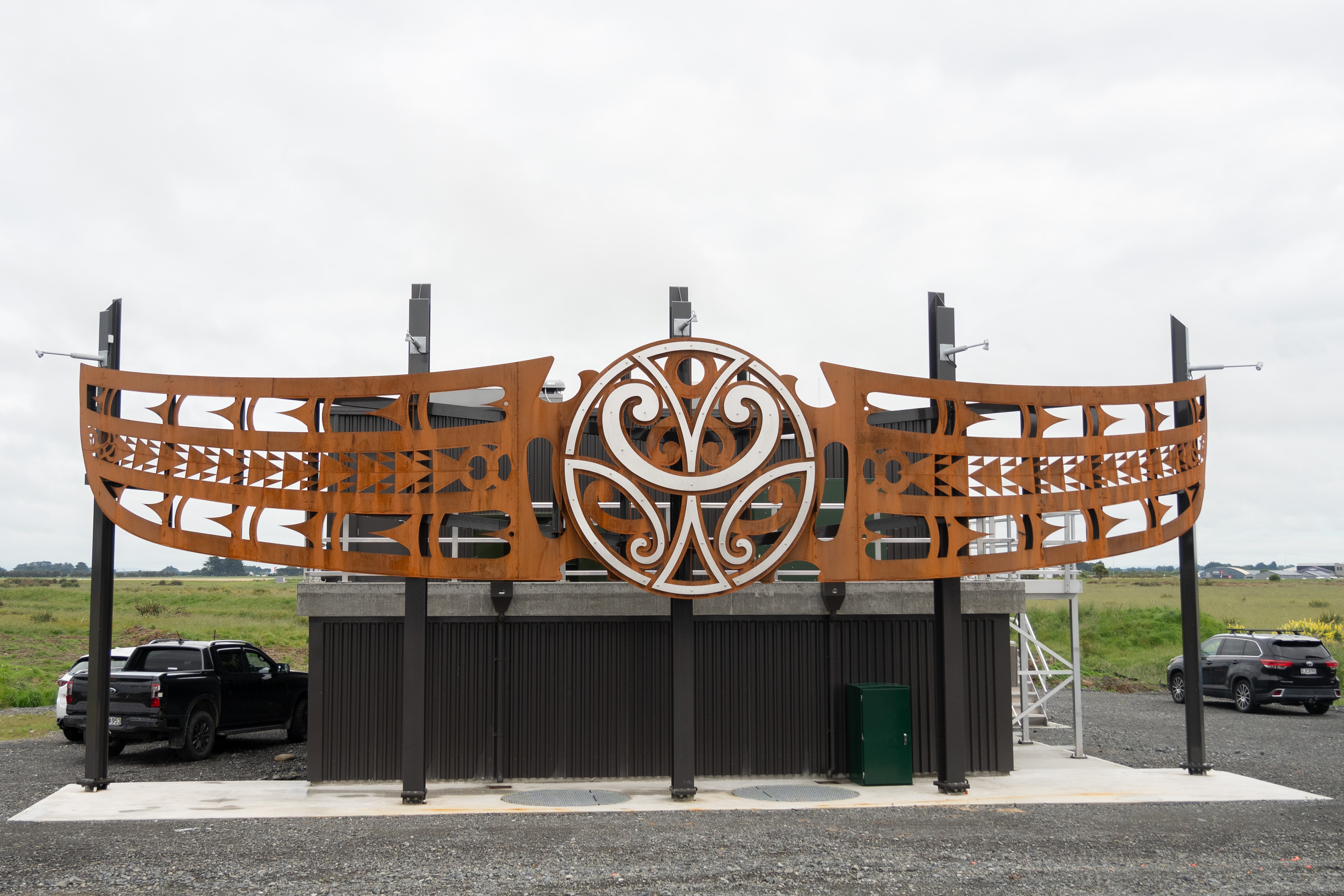 View of the artwork on the Stead Street pump house. It is two nets, meeting in the middle of a large round design, all made from steel.